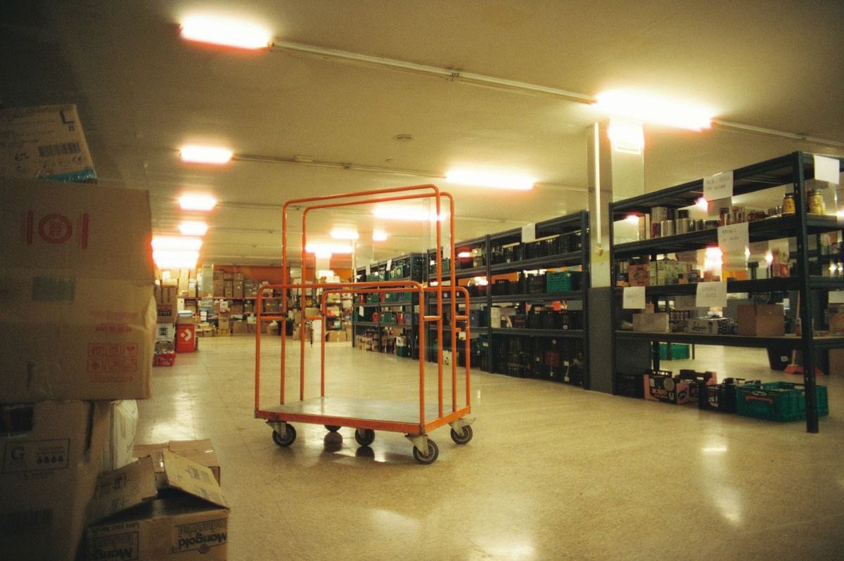 Wózek do kompletacji w alejce magazynu między półkami