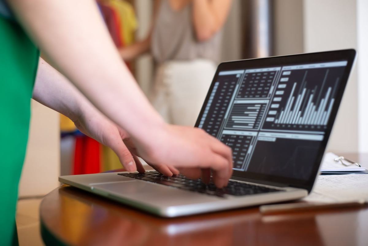 Dłonie wpisujące dane faktury na klawiaturze laptopa